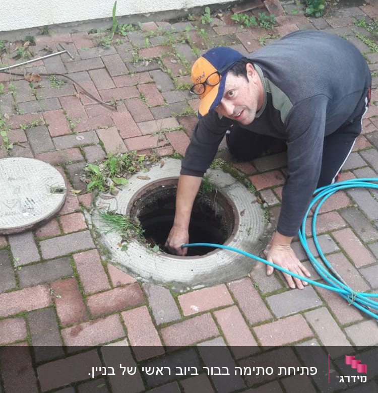 אדם עם צינור כחול בודק פתח ביוב